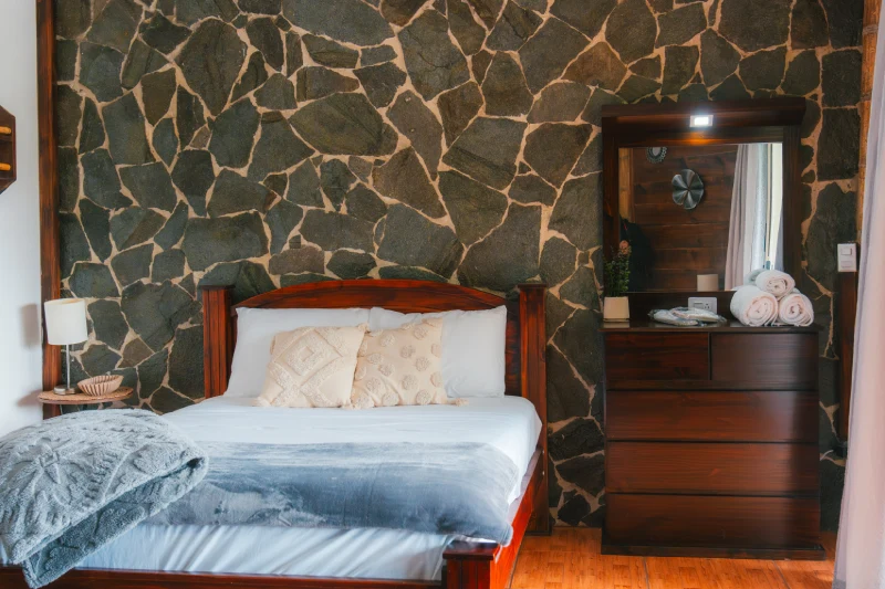 Penthouse bedroom with timber headboard and stone feature wall